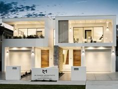 a modern house with two garages and lights on the front door at night time