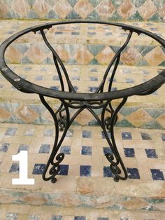 an iron table sitting on top of a tiled floor with the number 1 in front of it