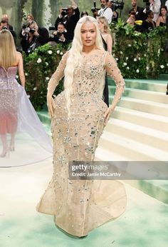 the blond haired lady is dressed in an elaborate gown and headpiece as she walks down the