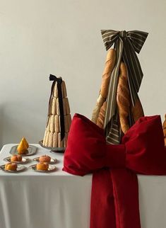 breads and pastries are arranged on a table with red velvet bow, which is tied around the edges