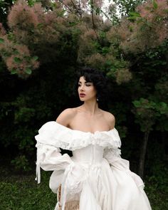 a woman in a white dress is posing for the camera