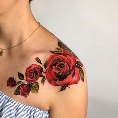 a woman's shoulder with red roses painted on her chest and arm, in front of a white wall