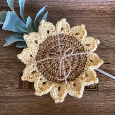 a crocheted sunflower with a string tied to it on top of a wooden table