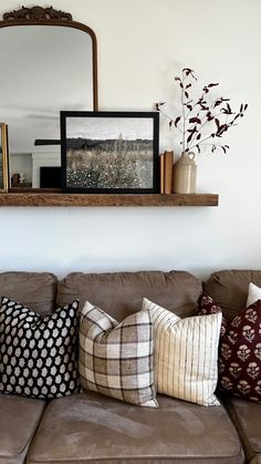 a living room with a couch, mirror and pictures on the wall above it's headboard