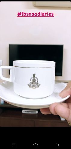 a person holding a white cup and saucer