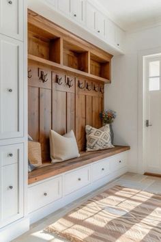 a wooden bench sitting in the middle of a room with white cupboards and drawers