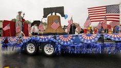 a parade float with american flags and decorations on it's flatbed, in the street