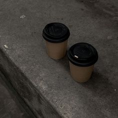 two coffee cups sitting on the ground next to each other