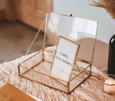 a table topped with a glass container filled with candles and a sign on top of it