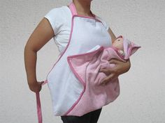 a woman holding a baby wrapped in a pink and white towel with a pink strap