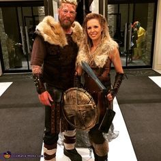 a man and woman dressed up as vikings pose for a photo together in front of a building