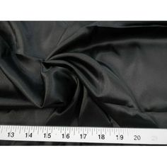 a ruler is next to a black satin material that looks like it has been cut in half