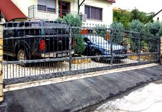 two cars parked in front of a house behind a fence