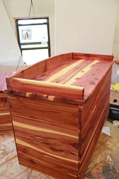 a large wooden box sitting on top of a hard wood floor next to a window