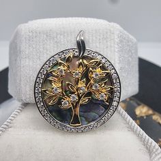 This enchanting 925 Silver Tree of Life Charm Pendant is a symphony of natural beauty and sparkling elegance. At its heart is the Tree of Life, a universal symbol of interconnectedness and growth, cast in radiant gold-tone over sterling silver. Each branch and leaf is delicately detailed, accentuated by sparkling crystals that mimic dewdrops catching the morning sun. The backdrop of vibrant abalone shell brings this symbol to life with its oceanic colors and swirling patterns, reminiscent of the Tree Of Life Round Jewelry For Anniversary, Elegant Tree Of Life Jewelry For Anniversary, Elegant White Gold Tree Of Life Jewelry, Silver Tree, Tree Of Life Pendant, Costume Jewelry Necklaces, Morning Sun, Crystal Charm, Sparkling Crystal