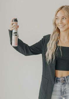 a woman holding up a spray bottle in her right hand