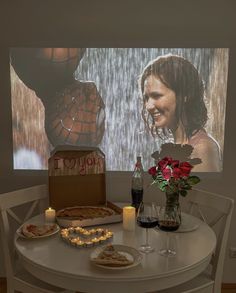 a table with two pizzas on it and some candles in front of the screen