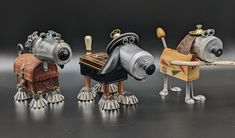 three metal toy animals sitting next to each other on a black surface with one holding a wooden object