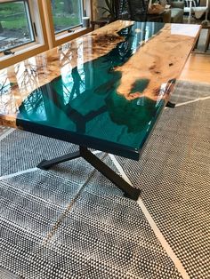 a table that is sitting on the floor in front of some windows and rugs