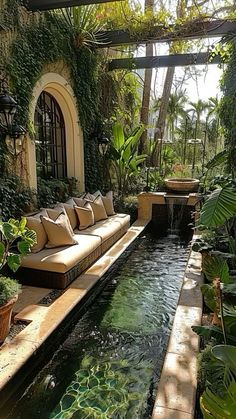 a living room filled with lots of plants next to a small pool in the middle of a patio