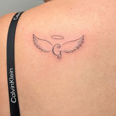 the back of a woman's shoulder with an angel tattoo on her left side