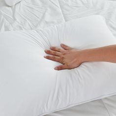 a person's hand resting on a white pillow