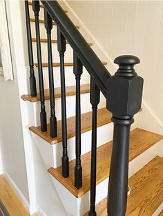 a cat sitting on top of a wooden stair case next to a banister in a house