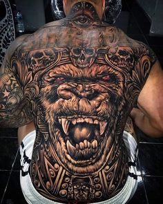 the back of a man's body with an elaborate tattoo design on his chest