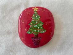 a red rock with a christmas tree painted on the side and a potted plant