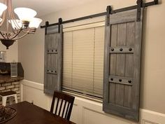 a dining room table and chairs with two sliding doors on the wall behind them that are open