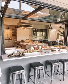 a kitchen filled with lots of counter top space next to a bar topped with stools