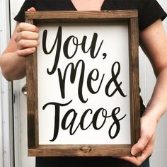 a woman holding up a sign that says you me and tacos in black ink