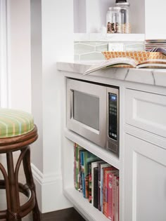 a small kitchen with a microwave on the counter and a bar stool in front of it