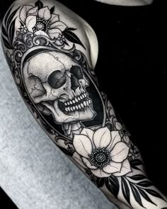 a black and white photo of a skull with flowers on it's arm, next to an iphone