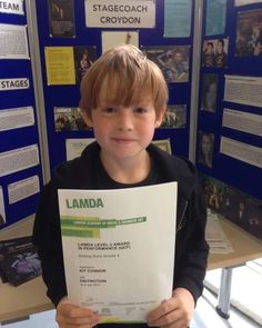 a young boy holding up a piece of paper