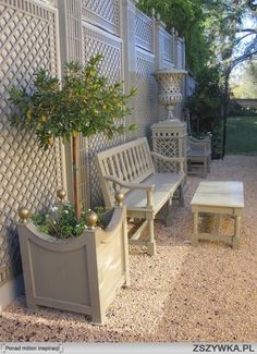 a white bench sitting next to a tree and a planter on top of a wooden table