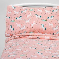 a pink bed with unicorns on it and stars all over the pillowcase,