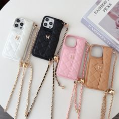 four cell phones with chains attached to them sitting on a table next to a book