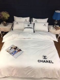 a white bed with chanel pillows and pictures on the comforter in front of it