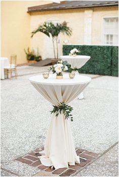 a table with flowers and candles on it sitting in front of a yellow building at the end of a walkway