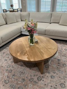 a living room filled with furniture and flowers in a vase on top of a coffee table