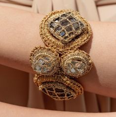 a close up of a person's arm wearing gold bracelets with diamonds on them