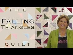 a woman standing in front of a quilt with the words falling triangles quilt on it