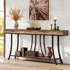 a console table with books, vases and candles on it in a living room