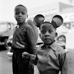 two young boys wearing mickey mouse ears standing next to each other