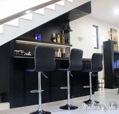 three black bar stools in front of a counter with bottles and liquor on it