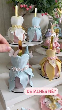 there are many small cakes on display with candles in the shape of dresses and bows