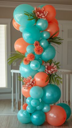 an arrangement of balloons, flowers and greenery is displayed on the floor in front of a staircase