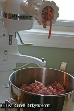 a large metal bowl filled with food on top of a counter next to a mixer