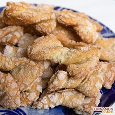 a blue and white plate filled with sugar covered donuts on top of a table